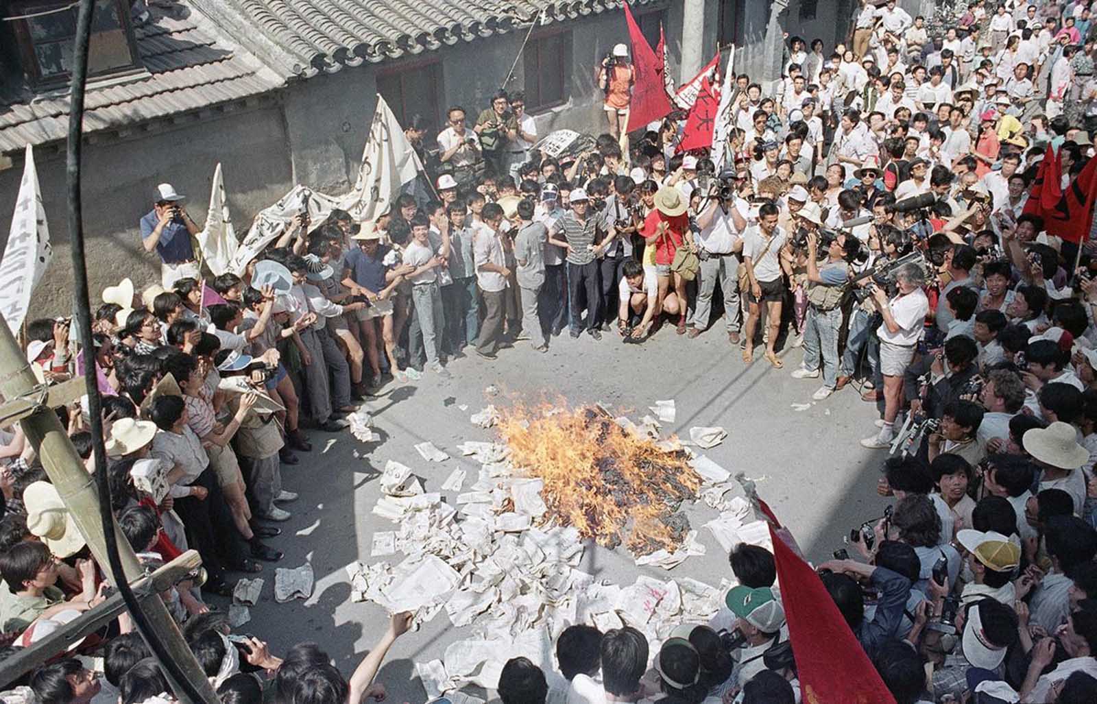 multid&atilde;o re&uacute;ne-se para ver grupo de estudantes, que se manifestavam na Pra&ccedil;a Tiananmen, queimar c&oacute;pias do Beijing Daily (Di&aacute;rio de Pequim) em frente dos escrit&oacute;rios do jornal em retalia&ccedil;&atilde;o contra artigos anti-estudantes/The Tiananmen Square protests: a huge crowd gathers to watch as student protestors burn copies of the Beijing Daily in retaliation for anti-student articles in front of the newspaper&rsquo;s offices, 2 Junho/June 1989